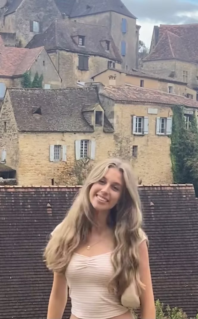 Penelope Purdy, pianist, photographed outdoors in front of a hillside village of stone houses.